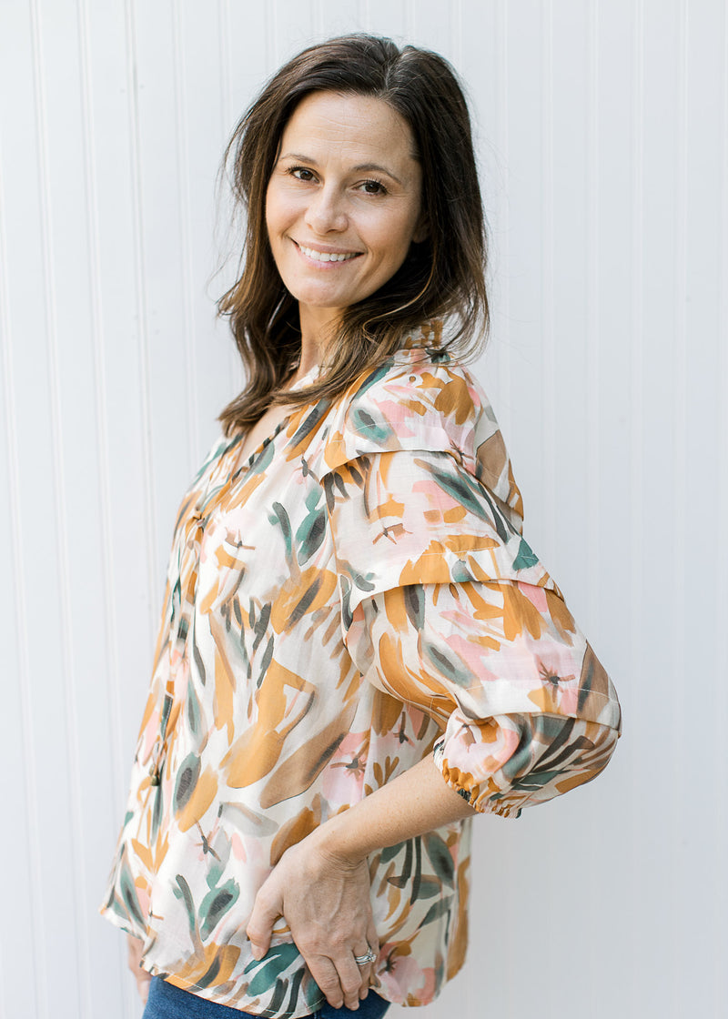 Model wearing a cream top with pink, mustard and sage floral, 3/4 sleeve with elastic cuff.