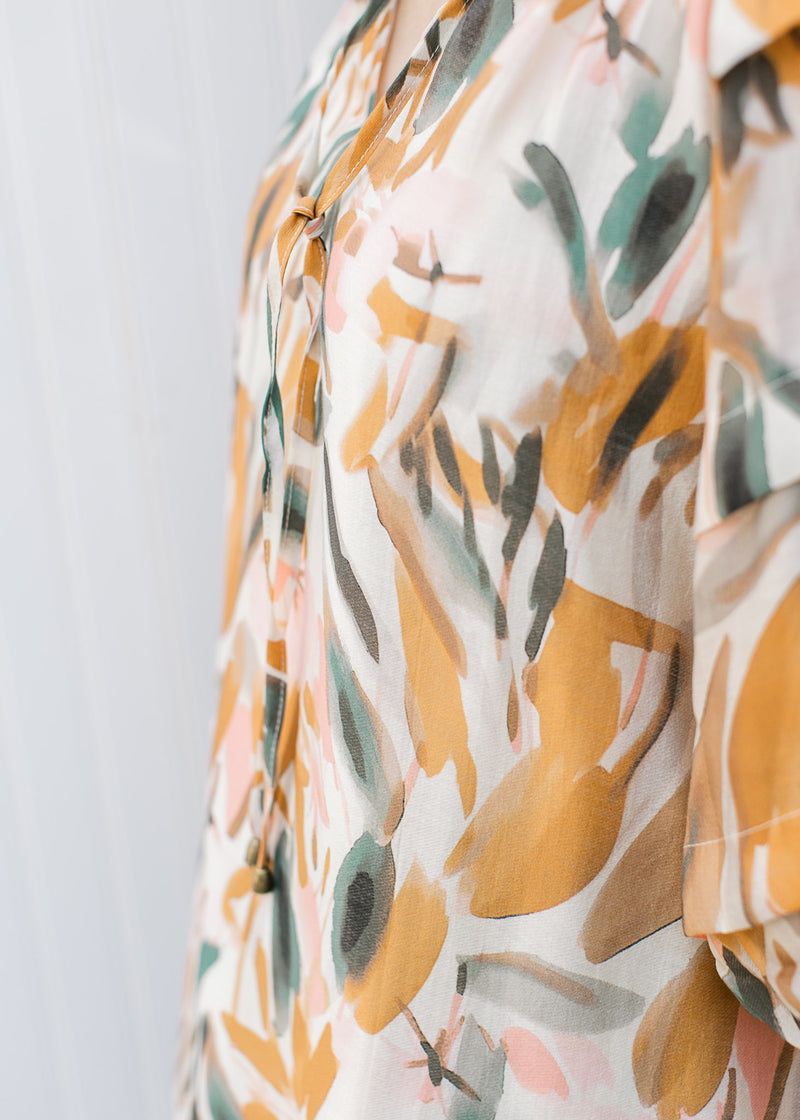 Close up of cream top with mustard, pink and sage watercolor floral. 