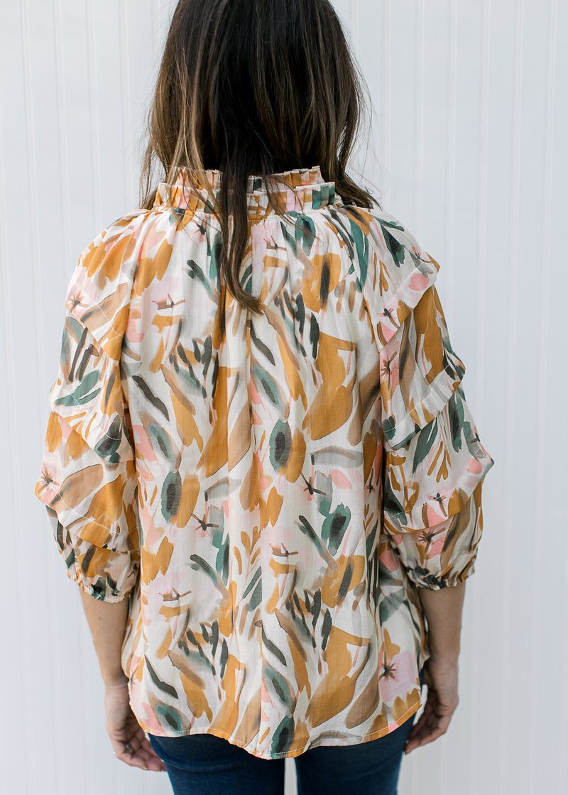 Back view of cream top with watercolor floral, tiered ruffle at neck and 3/4 sleeves.