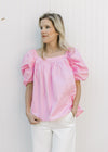 Model wearing a pink top with micro pleated bodice and back and short elastic sleeves.