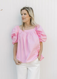 Model wearing a pink top with micro pleated bodice and back and short elastic sleeves.