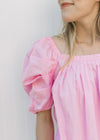 Close up of square neck and micro pleating on the bodice of a short sleeve pink top.