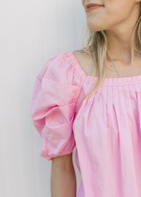 Close up of square neck and micro pleating on the bodice of a short sleeve pink top.