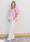 Model wearing white jeans and a pink top with micro pleated bodice and back and short sleeves.