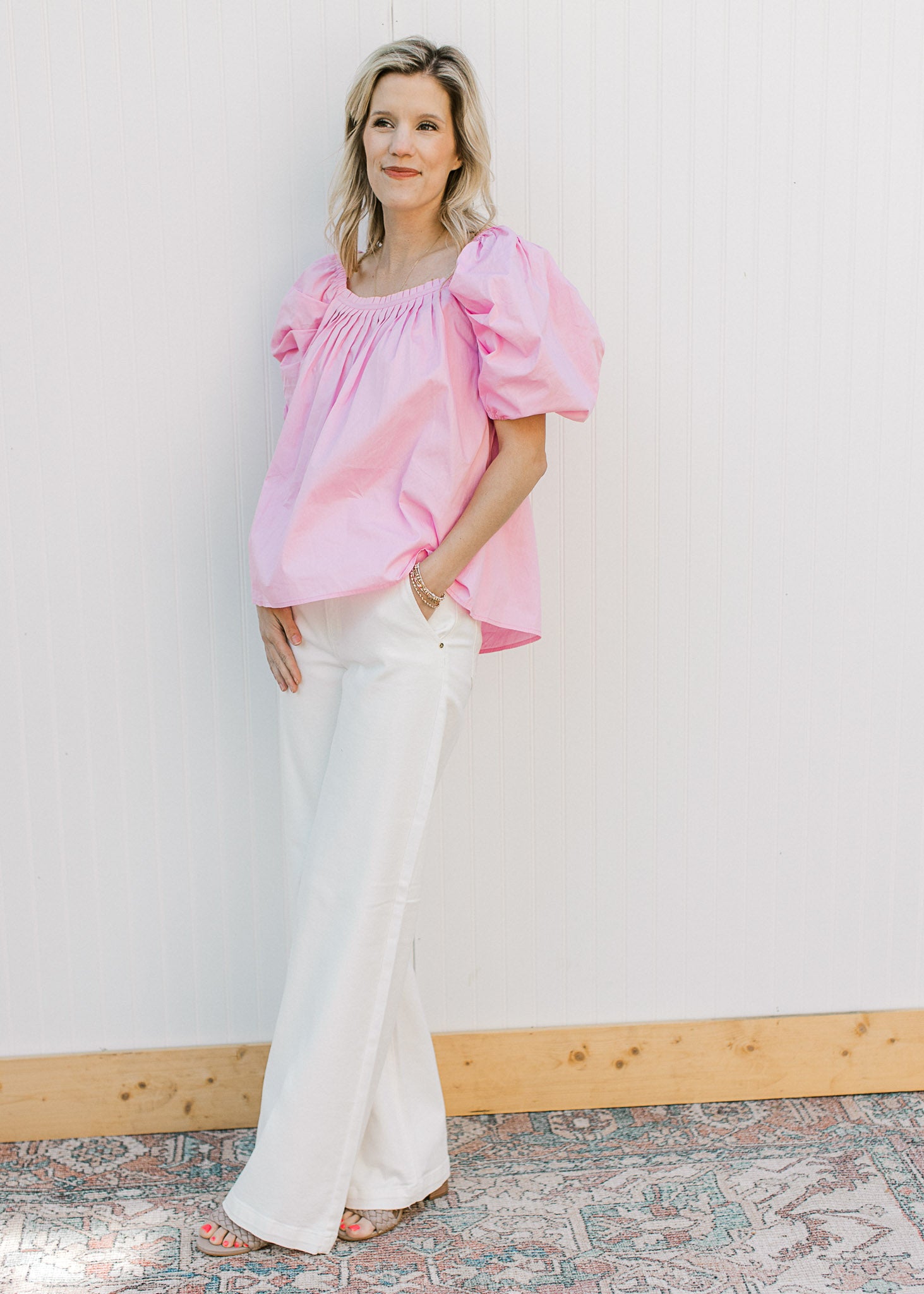 Model wearing white jeans and a pink top with micro pleated bodice and back and short sleeves.