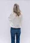 Back view of Model wearing a open knit sweater with a neutral color, long sleeves and a round neck.