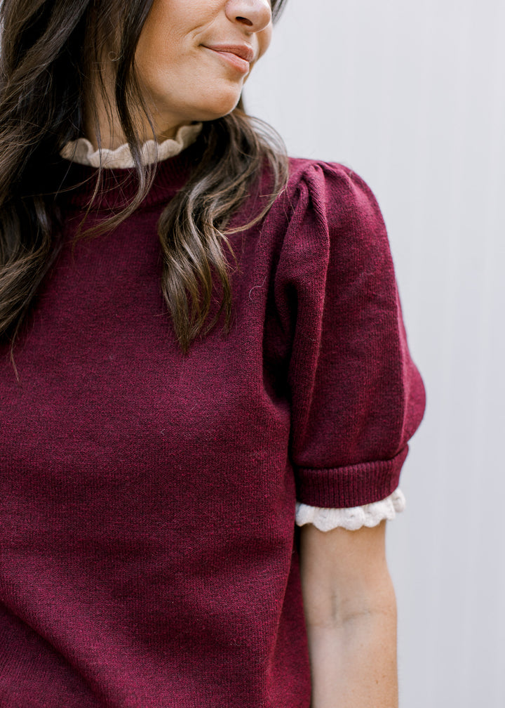 Close-up of Burgundy Crochet Layer Top showing pleated puff shoulder, ribbed sleeve cuff and cream scalloped trim.