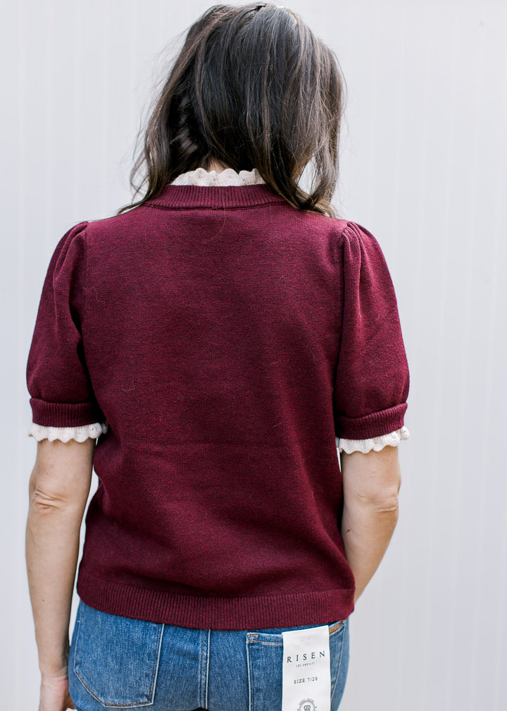 Back view of the Burgundy Crochet Layer Top showing short puff sleeves, cream neckline and cuff accents, and a ribbed hem.