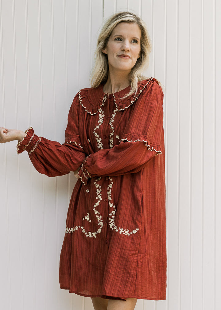Model wearing a long sleeve burgundy dress with cream floral, button front and exaggerated collar. 