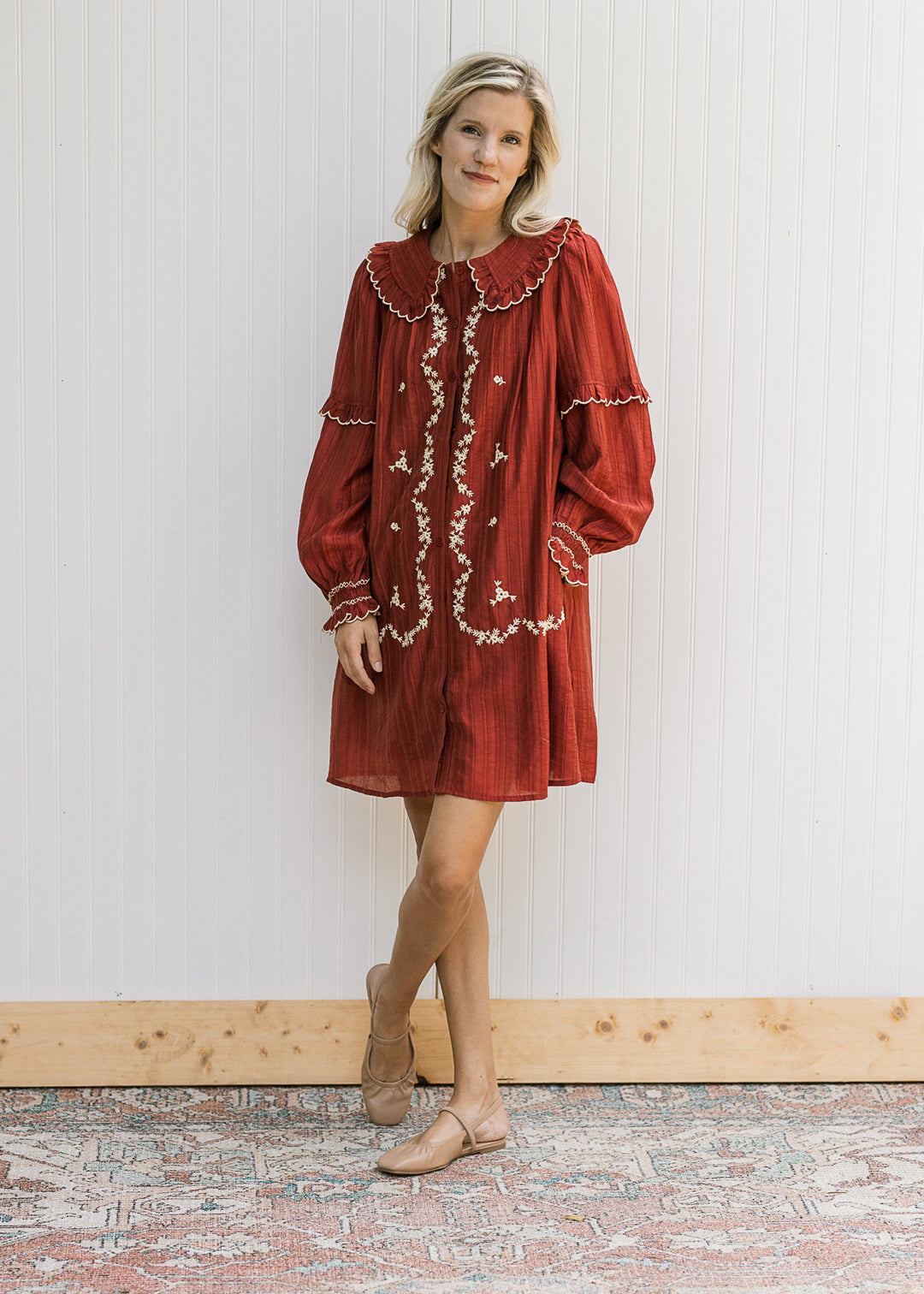 Model wearing flats and a long sleeve burgundy dress with cream floral and exaggerated collar. 