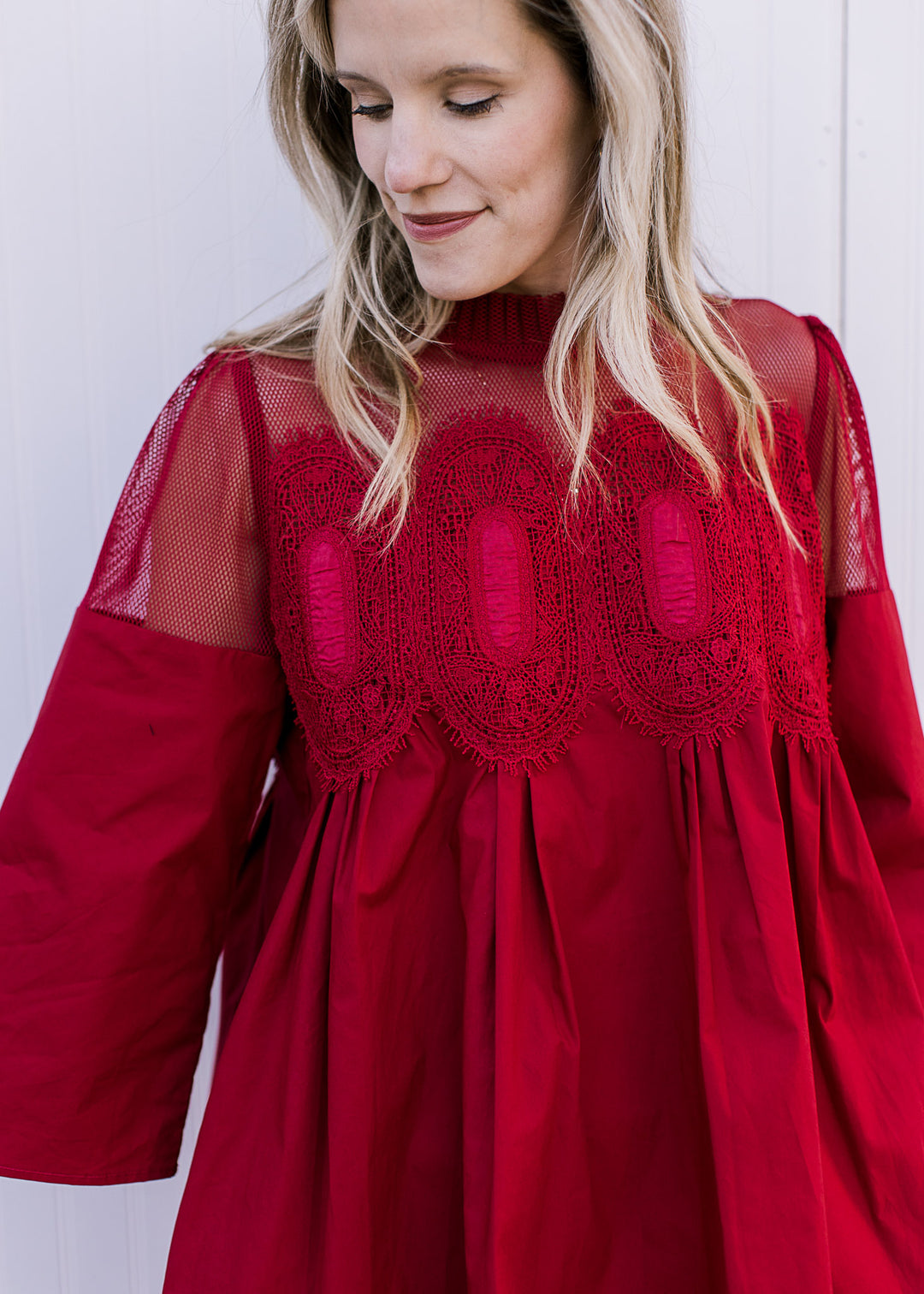 Close up of mesh shoulders and neck with embroidered medallions at bust of red above the knee dress.