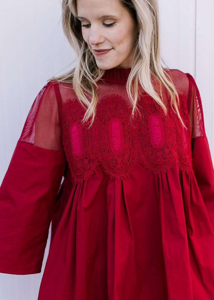 Close up of mesh shoulders and neck with embroidered medallions at bust of red above the knee dress.