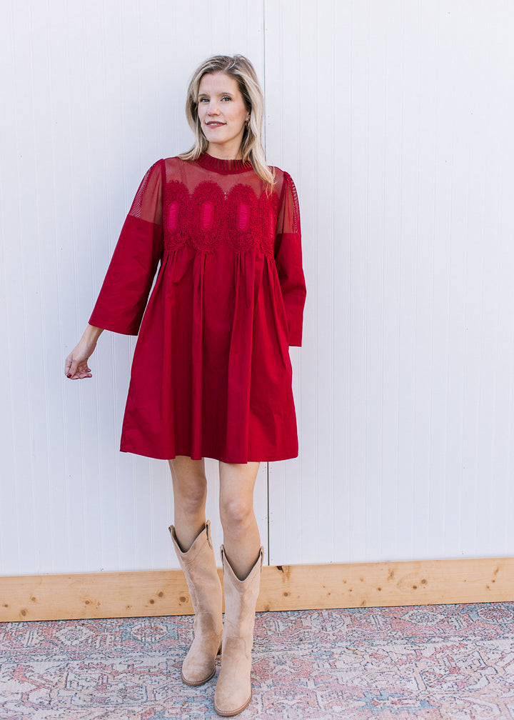 Model wearing boots and a Burgundy dress with 3/4 sleeves and mesh lace neck with medallions.