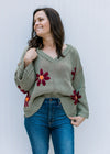 Model wearing a sage sweater with burgundy flowers, exposed hem, long sleeves and  v-neck.