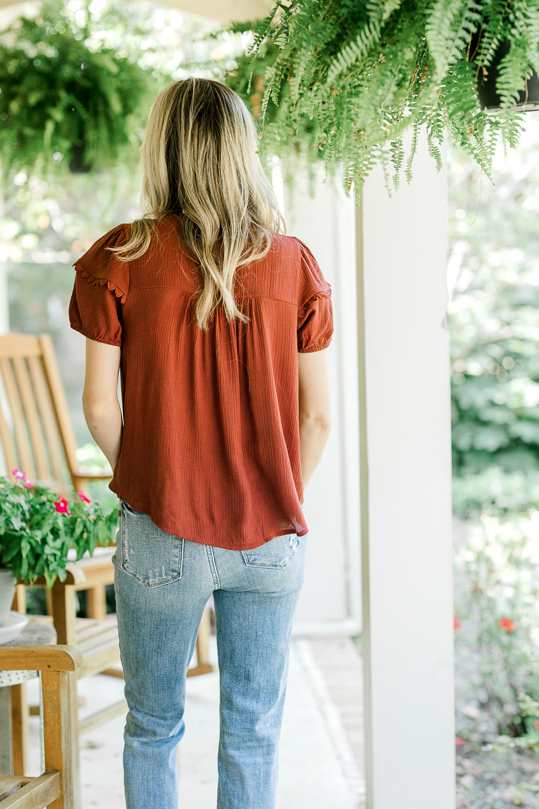 Back view of Model wearing a burgundy short sleeve top with scalloped detailing and v-neck with tie.
