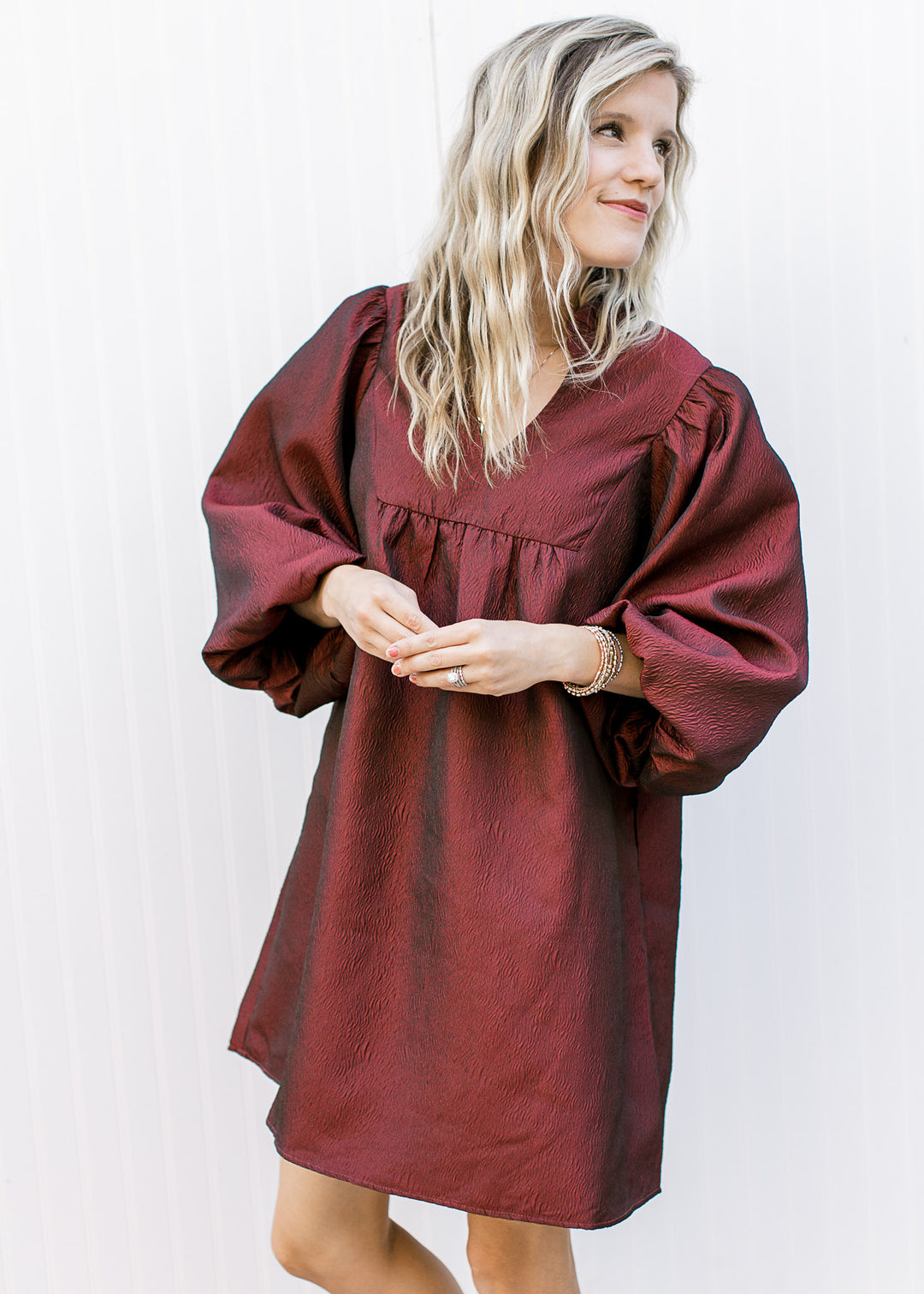 Model wearing an above the knee burgundy dress with a v-neck, 3/4 bubble sleeves.