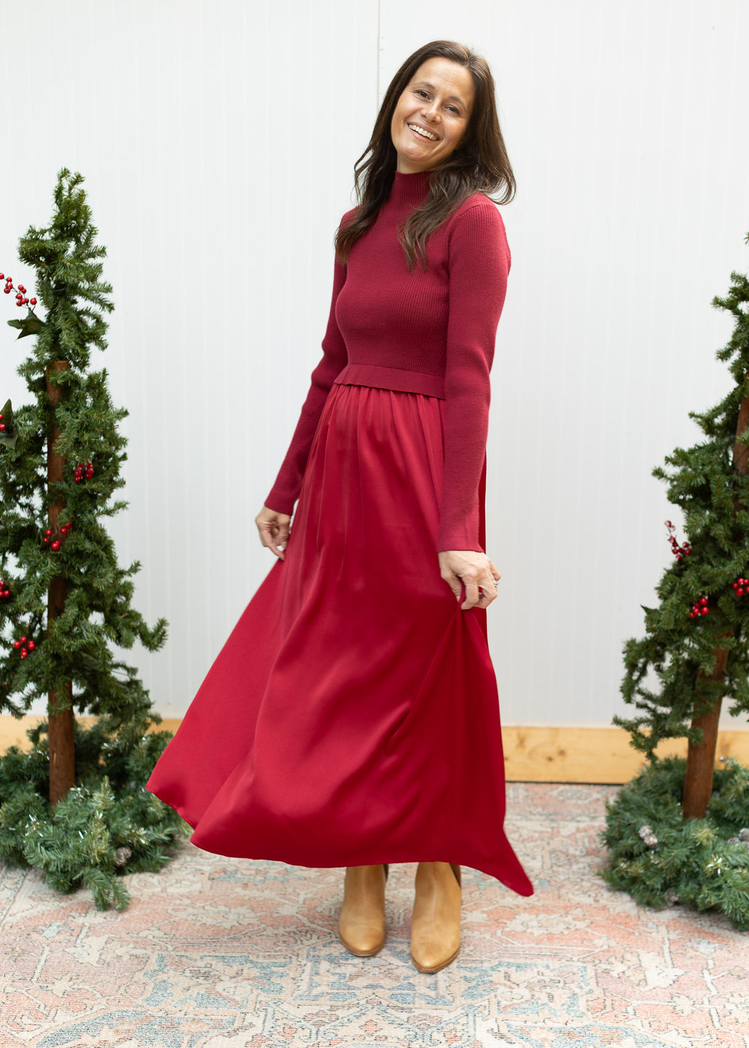 Burgundy mock neck sweater dress with long sleeves and a satin maxi skirt fanned out to show its drape.