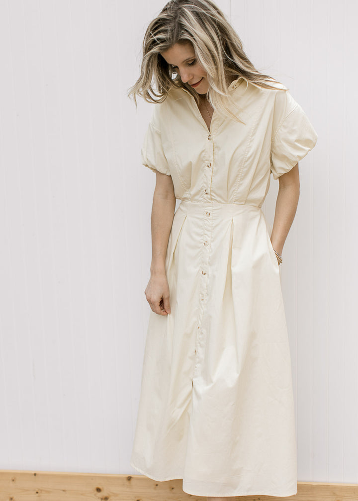 Model wearing a soft yellow midi with a button-front, elastic waist with tie and short sleeves.