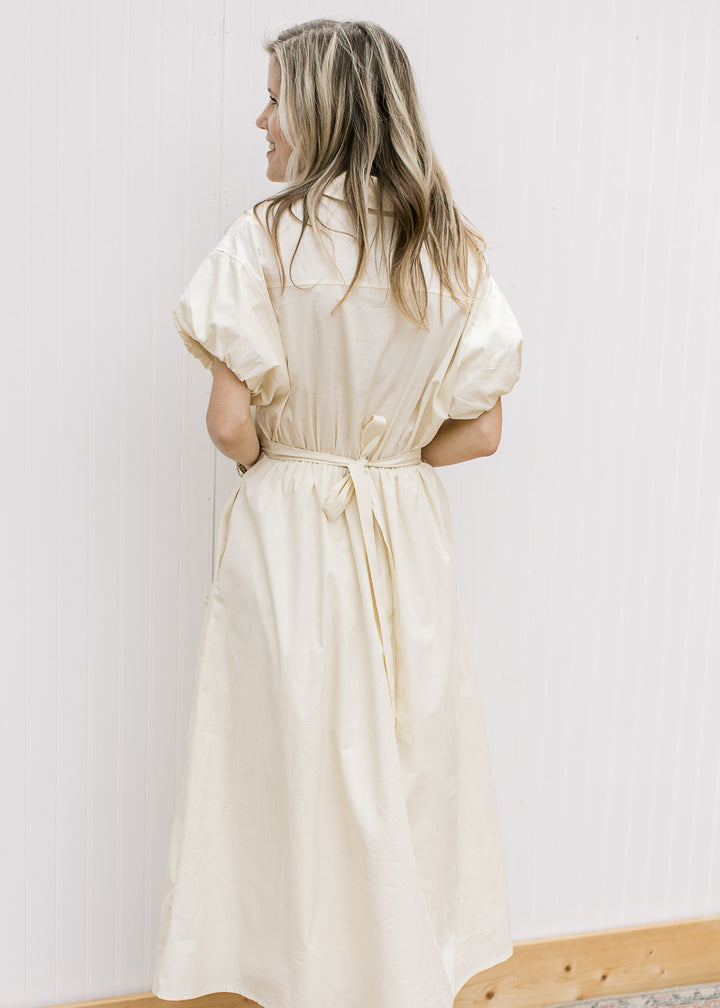 Back view of Model wearing a soft yellow midi with elastic waist with tie and bubble short sleeves.