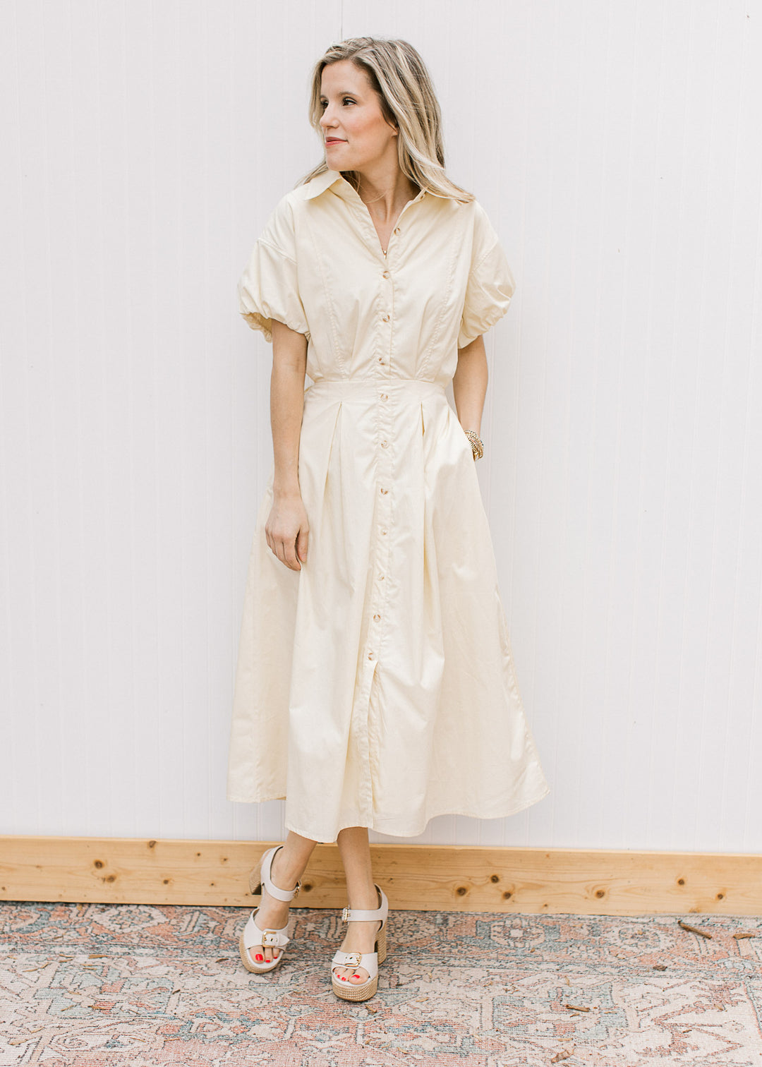Model wearing heels and a soft yellow midi with buttons, elastic waist with tie and short sleeves.