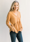 Model wearing jeans with a ribbed butterscotch top with long sleeves, a v-neck and a babydoll fit.