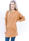 Model wearing a deep caramel colored tunic with patch pockets and long sleeves. 