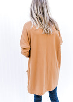 Back vie Model wearing a deep caramel colored tunic with patch pockets and long sleeves. 