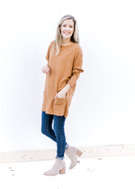 Model wearing jeans, booties and a deep caramel colored tunic with patch pockets and long sleeves. 