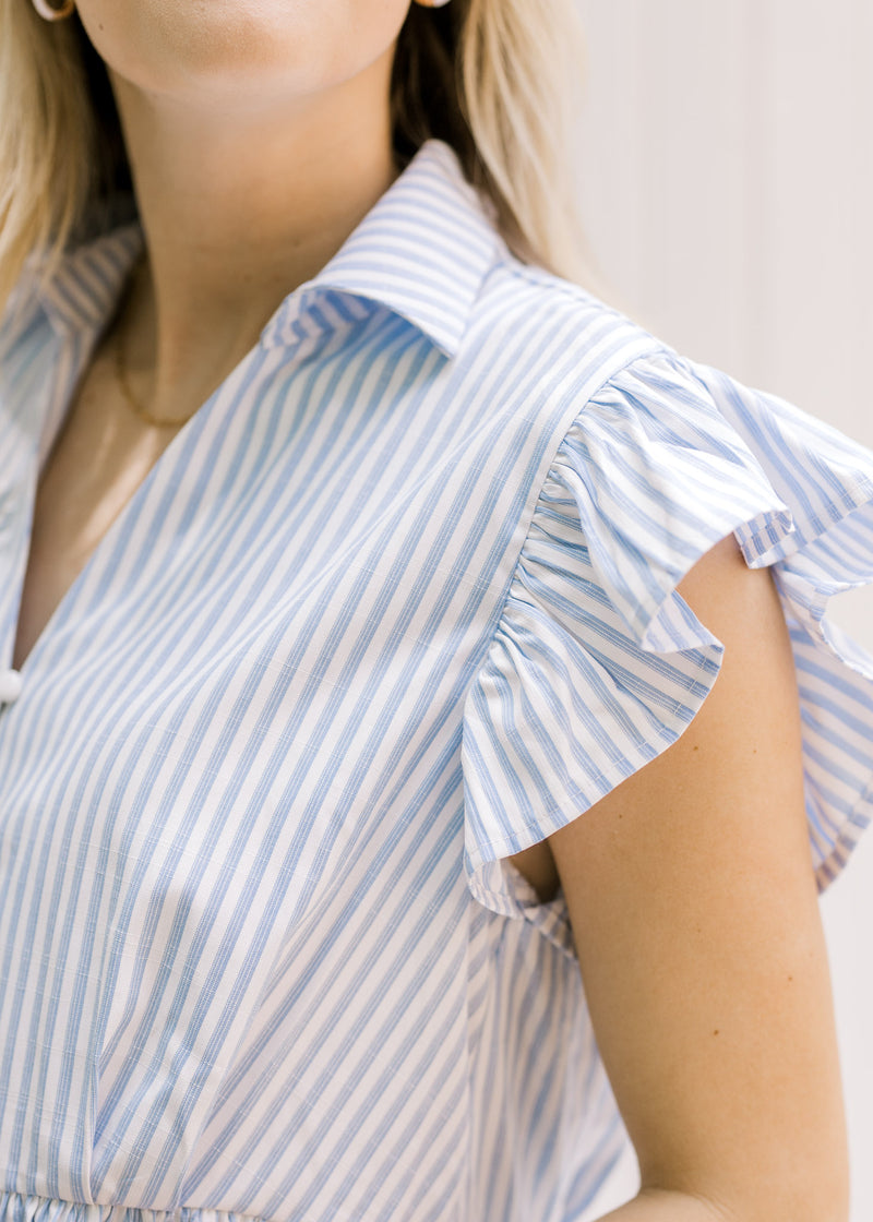 Close up view of ruffle short sleeve on a blue and white striped top with a v-neck. 