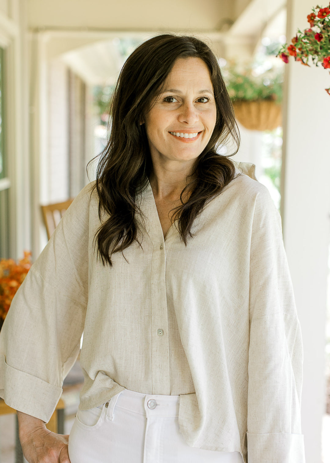 Model wearing an oatmeal top with button front, v-neck, cuffed 3/4 sleeves and a high-low hem.
