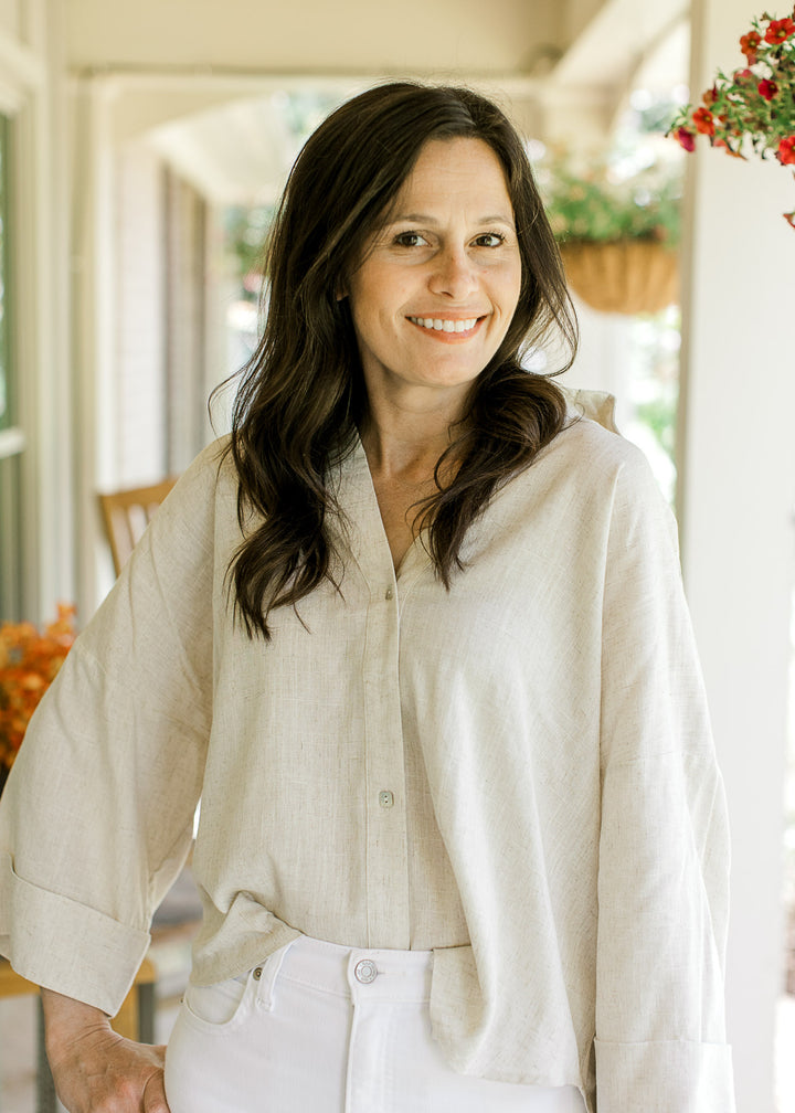 Model wearing an oatmeal top with button front, v-neck, cuffed 3/4 sleeves and a high-low hem.