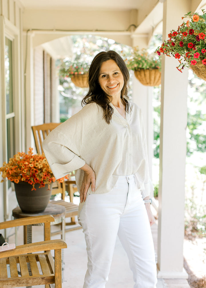 Model wearing white pants and an oatmeal top with button front, 3/4 sleeves and a high-low hem.