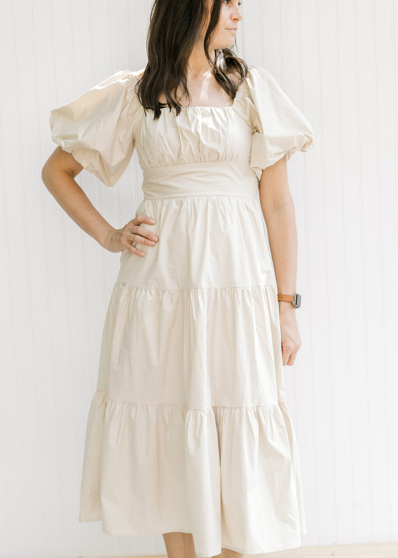 Model wearing a champagne  midi with bubble short sleeves, square neck and a smocked back.