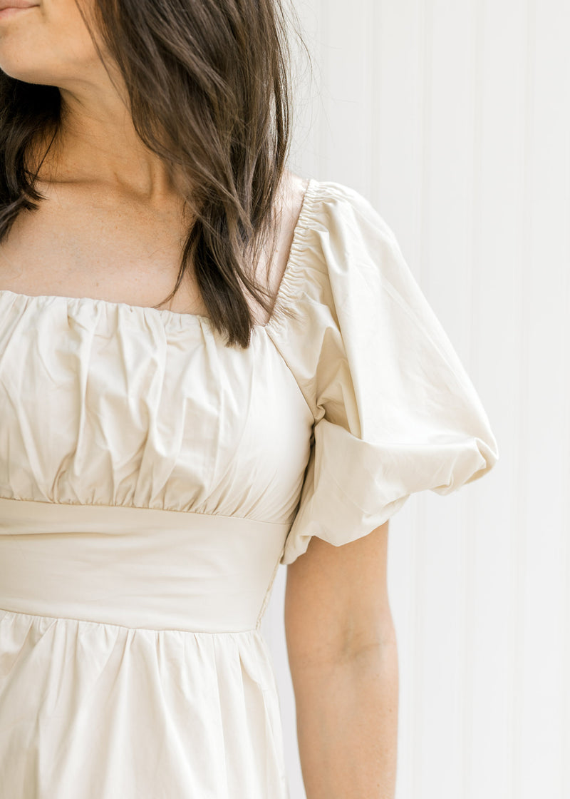 Close up view of bubble short sleeve and square neckline on a model in a champagne dress.