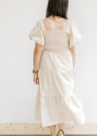 Back view of model in a champagne dress with a smocked back and bubble short sleeves.