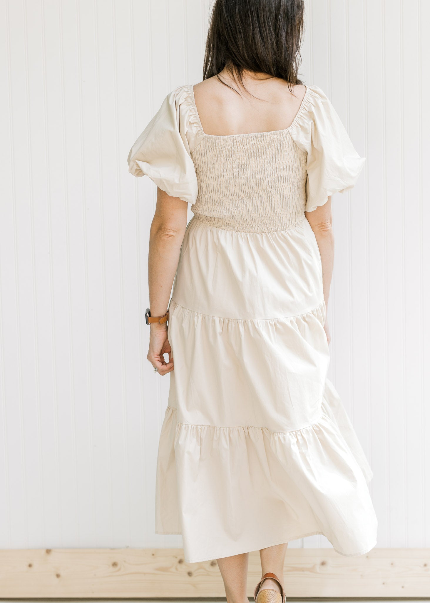 Back view of model in a champagne dress with a smocked back and bubble short sleeves.
