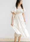 Model twirling in a champagne midi with a square neckline and short puff sleeves. 