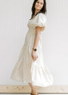 Model wearing a tiered champagne midi dress with short puff sleeves and a smocked back. 