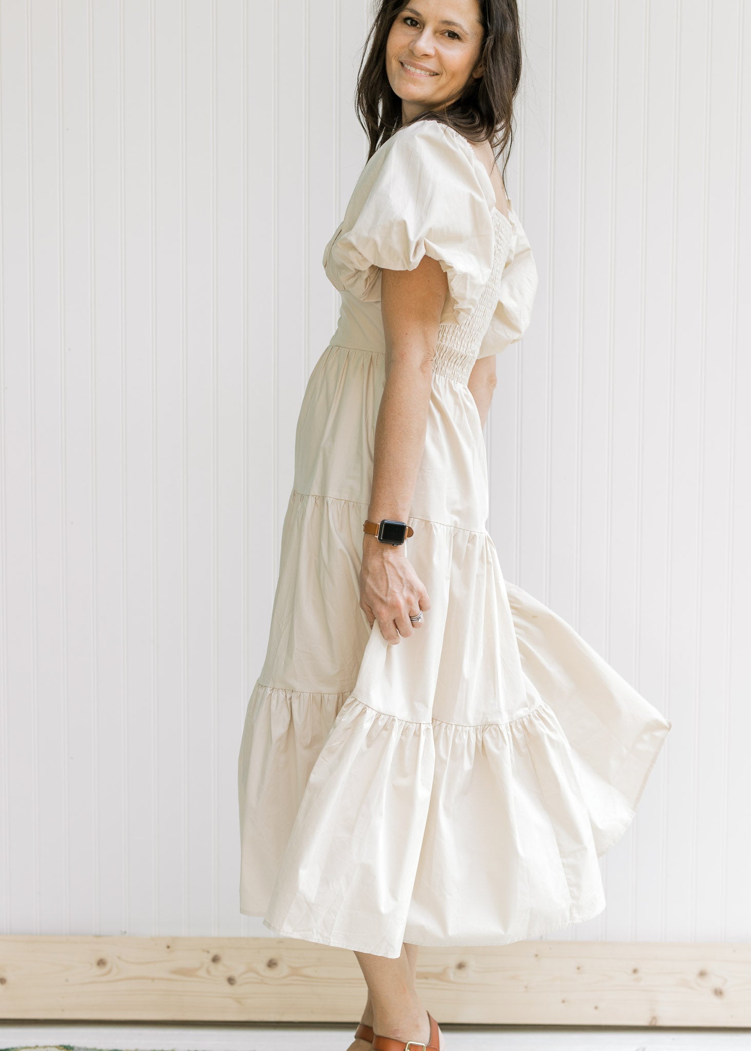 Side view of Model wearing a champagne tiered midi with bubble short sleeves and a square neck.