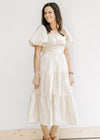 Model wearing a champagne tiered midi with bubble short sleeves, square neck and a smocked back. 