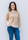 Model wearing a cream and camel checked sweater with long sleeves and round neck.