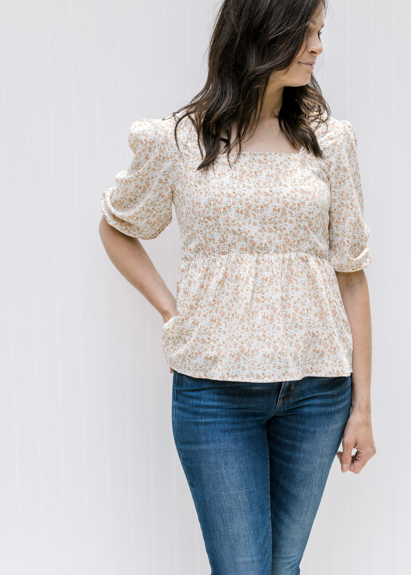 Model wearing a fully lined white top with a camel floral pattern, square neckline and 3/4 sleeves. 
