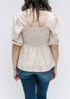 Back view of smocking on a model wearing a white top with a camel floral pattern and 3/4 sleeve.