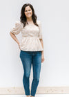 Model wearing jeans with a white top with a camel floral pattern, square neckline and 3/4 sleeves. 