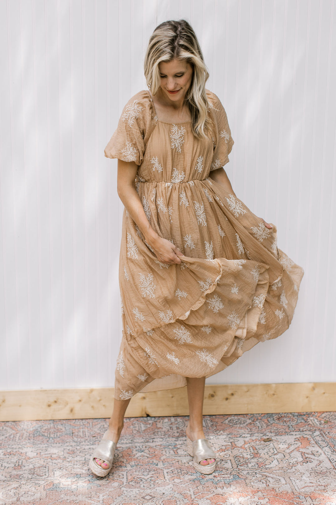 Model wearing wedges with a camel dress with white embroidered flowers and bubble short sleeves.