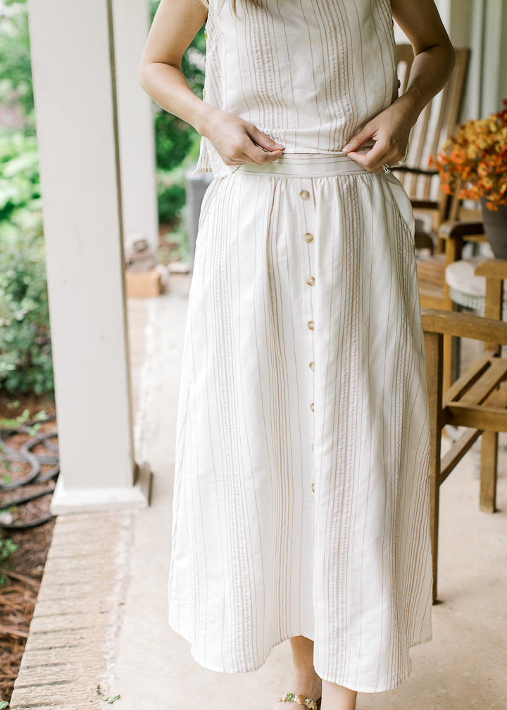 Close up of a cream midi skirt with camel stripes, buttons down front and elastic back. 