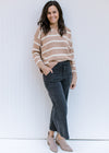 Model wearing jeans and booties and a camel sweater with cream stripes and split hem sleeve. 