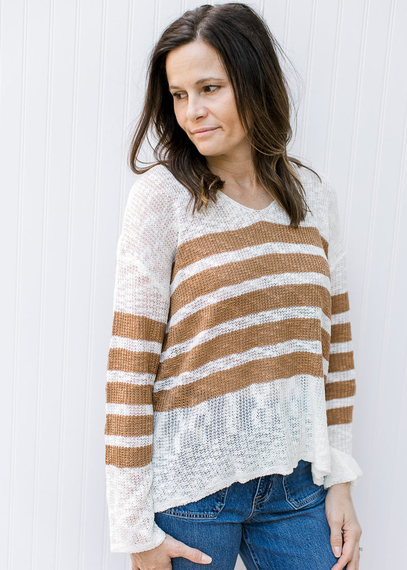 Model wearing a cream lightweight top with camel stripes, v-neck and long sleeves. 