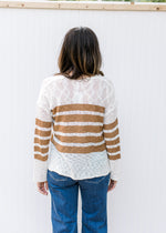 Back view of Model wearing a cream lightweight top with camel stripes, v-neck and long sleeves. 