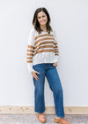 Model wearing jeans and mules with a cream top with camel stripes, v-neck and long sleeves. 